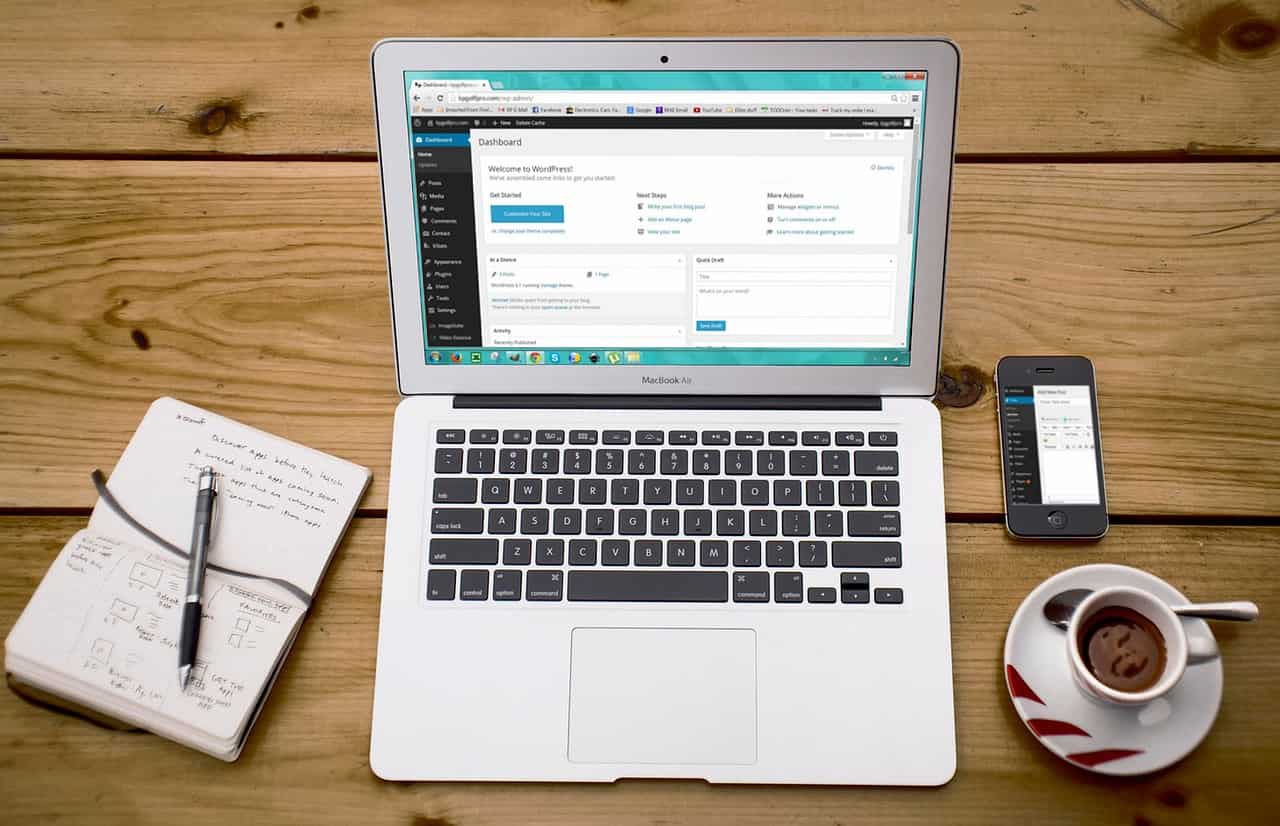 Kurs online tworzenie strony internetowej wordpress. Laptop z włączonym wordpressem, zeszyt i kawa leżą na biurku.