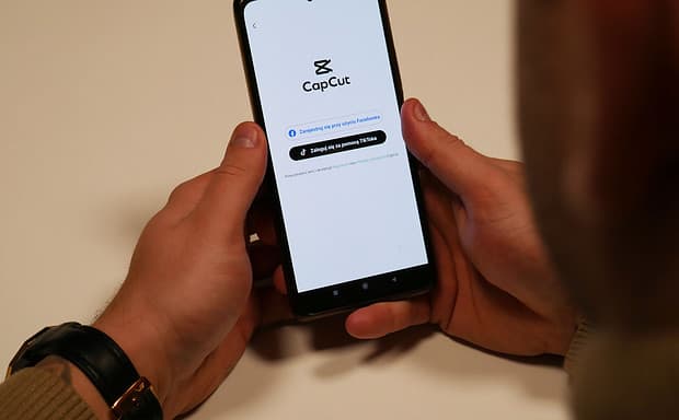 Kurs capcut - montaż filmów na telefonie. Osoba trzyma w dłoniach telefon z włączoną aplikacją CapCut.