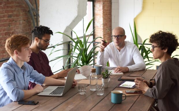 Kurs online pewność siebie w komunikacji. Cztery osoby dyskutują przy stole.