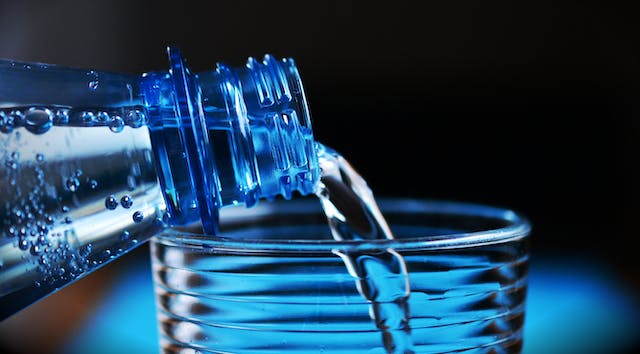 Woda z butelki jest nalewana do kubka.